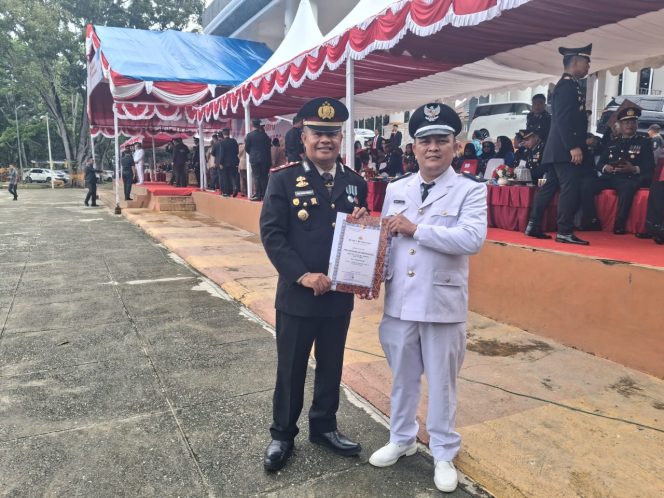 
 Kepala Desa Paku Jaya, Endang, A.Ma.Pd., bersama Kapolsek Bondoala, IPTU MH Payapo, S.Pd., M.H., CPm., usai menerima penghargaan yang diberikan oleh Kapolres Konawe. Foto: Istimewa
