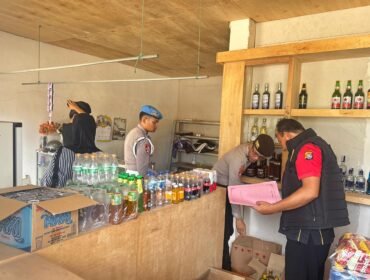 Personel Satgas Gakkum Operasi Pekat Anoa 2026 Polres Konawe Utara mengamankan 12 botol miras yang disita dari Toko Sahirman di Andowia. Foto: Istimewa  
