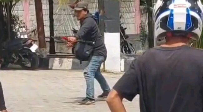 Tampak seorang pria berjaket hitam memegang senjata tajam jenis parang mengamuk di SPBU Wulele Kendari. Foto: Istimewa.