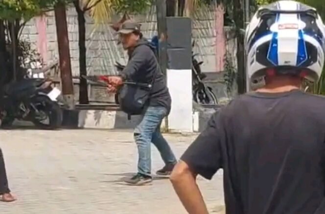 
 Tampak seorang pria berjaket hitam memegang senjata tajam jenis parang mengamuk di SPBU Wulele Kendari. Foto: Istimewa.